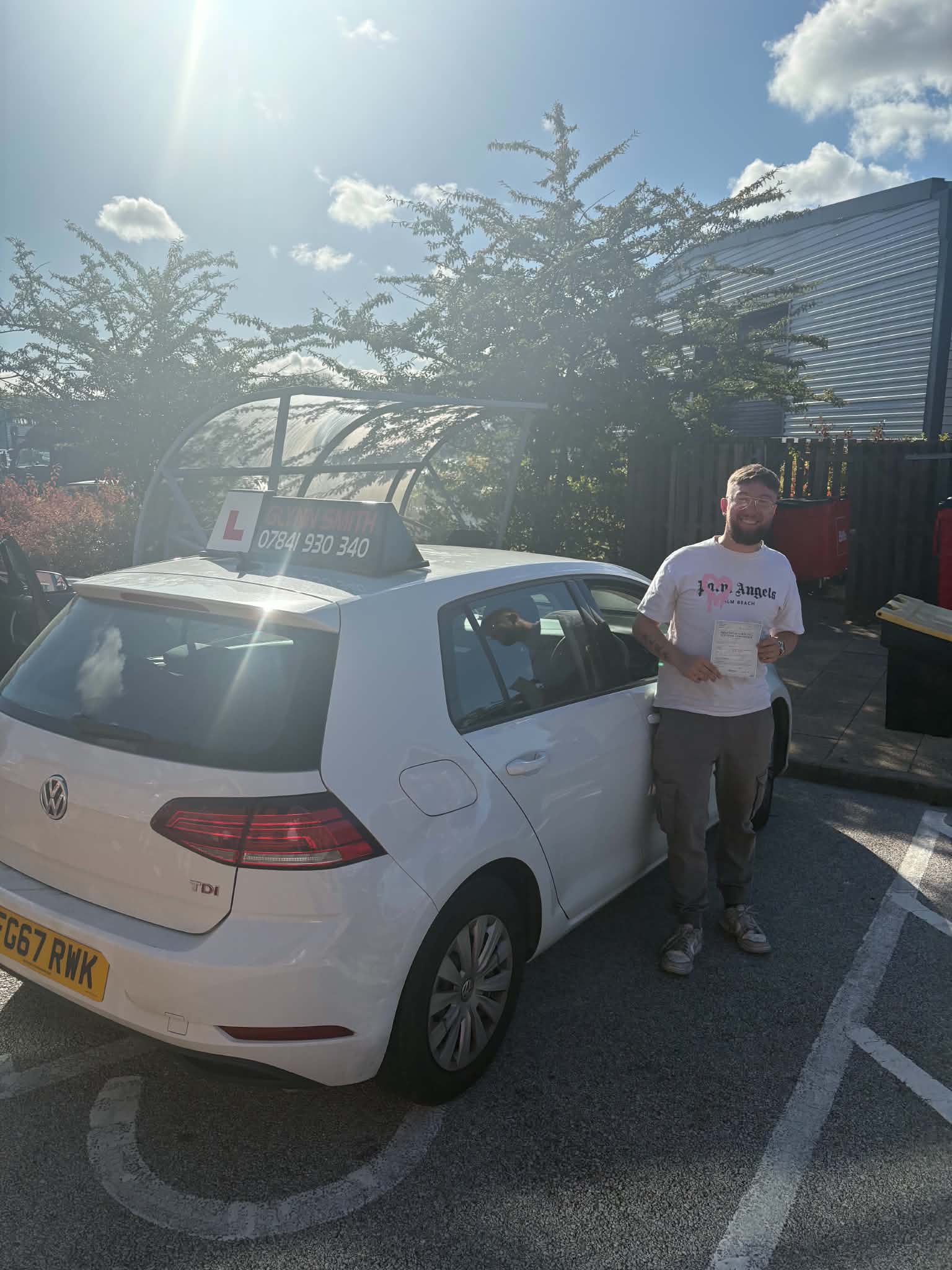 Elliot beside a black learner car, holding a certificate.